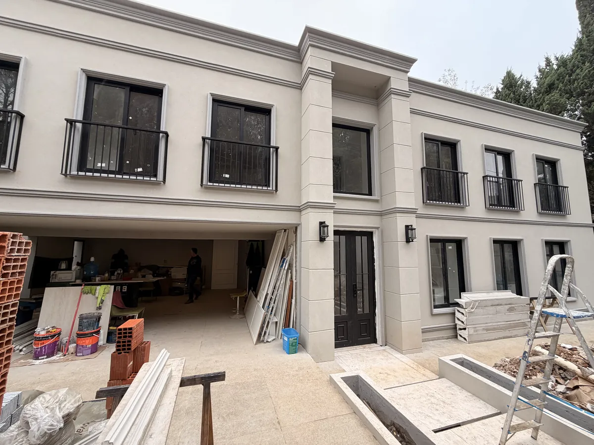 Depois: a lateral da casa com portas e janelas pretas instaladas, guarda-corpos e o piso ainda em acabamento.